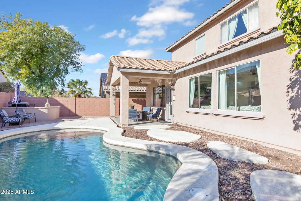 view of swimming pool featuring ceiling fan and a patio