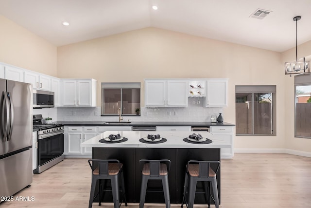 kitchen featuring appliances with stainless steel finishes, a center island, a breakfast bar area, and decorative light fixtures