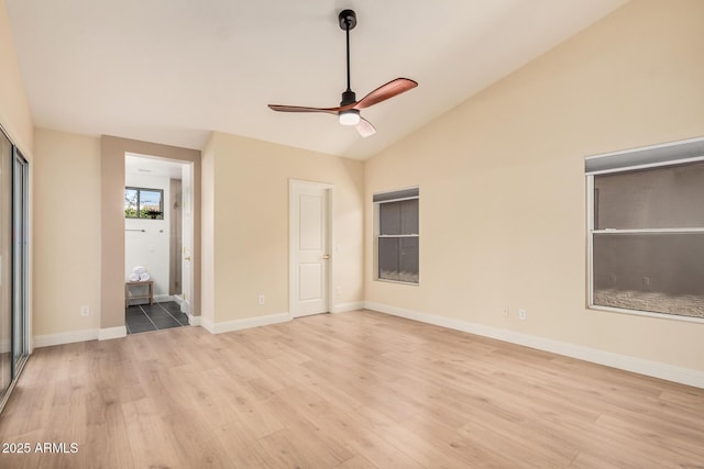 unfurnished bedroom with lofted ceiling, ensuite bathroom, and light wood-type flooring