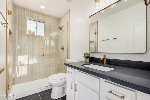 bathroom featuring tile patterned flooring, vanity, a shower with shower door, and toilet