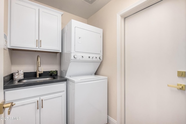 laundry room with cabinets, stacked washer / drying machine, and sink