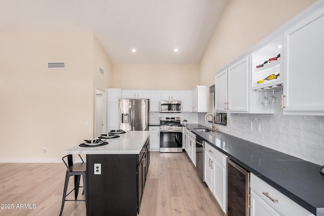 kitchen featuring appliances with stainless steel finishes, sink, wine cooler, white cabinets, and a center island