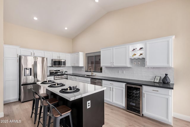 kitchen featuring sink, stainless steel appliances, a center island, wine cooler, and white cabinets