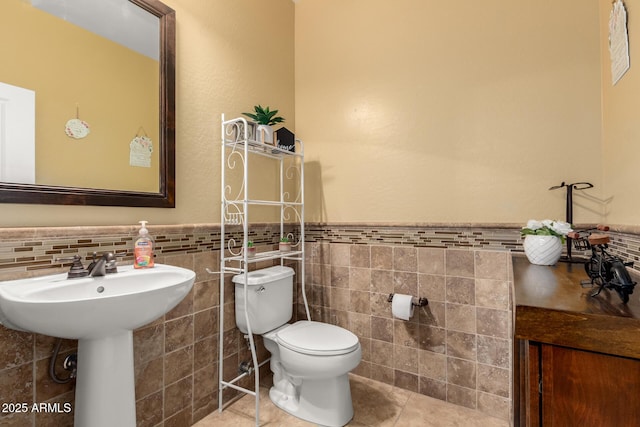 18171 W Marshall Ln, Surprise, AZ 85388 - half bath featuring a wainscoted wall, tile patterned floors, toilet, and tile walls
