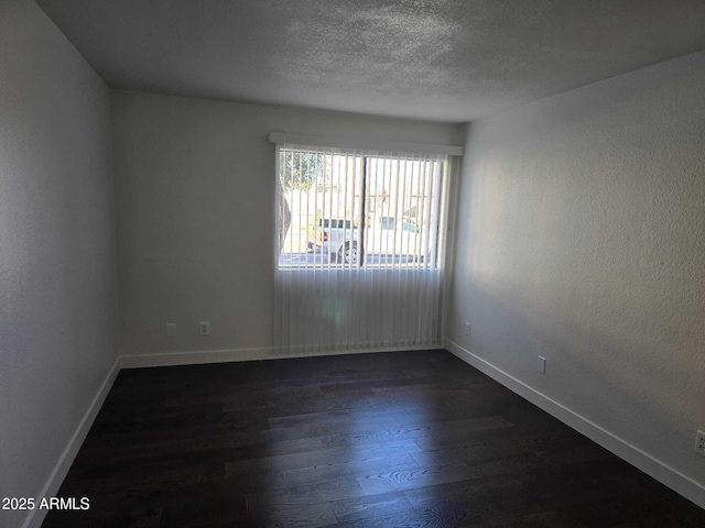 spare room featuring a textured ceiling and dark wood-type flooring