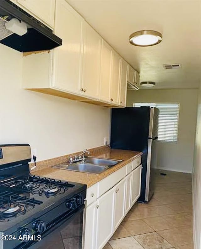 kitchen featuring under cabinet range hood, white cabinetry, range with gas stovetop, and a sink