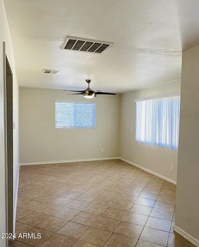 spare room featuring ceiling fan, baseboards, visible vents, and a healthy amount of sunlight