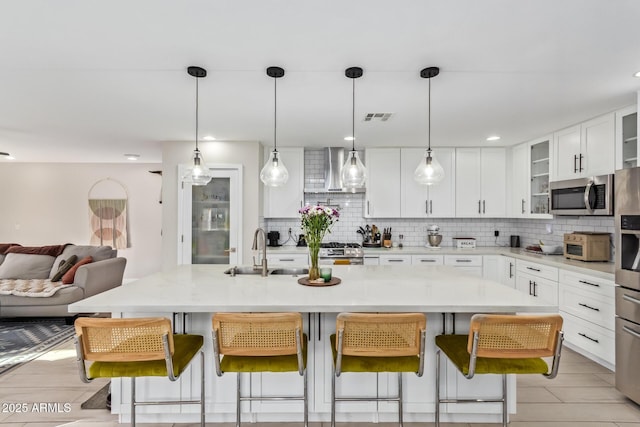 kitchen with stainless steel appliances, visible vents, decorative backsplash, a sink, and a kitchen breakfast bar