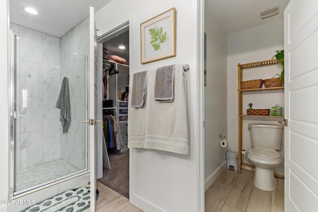 full bathroom with toilet, a spacious closet, a marble finish shower, and visible vents