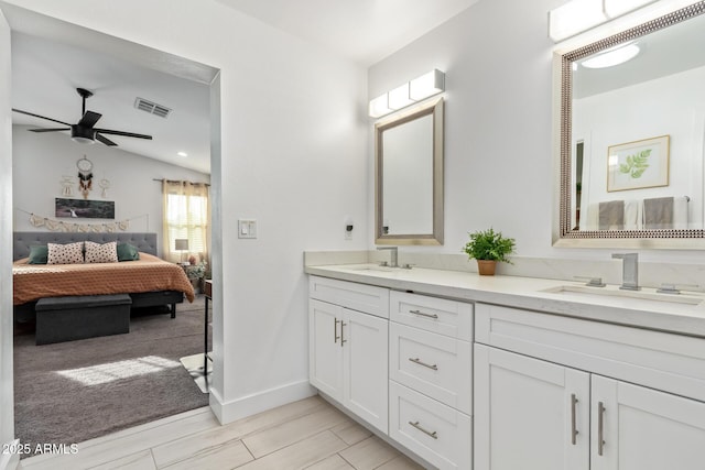 ensuite bathroom with ceiling fan, a sink, visible vents, and connected bathroom