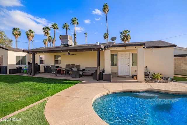 back of house with a patio, outdoor lounge area, a ceiling fan, a lawn, and stucco siding