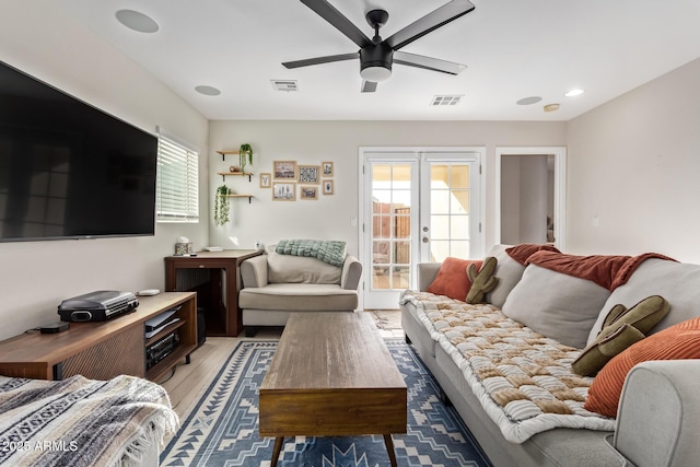 living room featuring ceiling fan, plenty of natural light, visible vents, and light wood-style floors