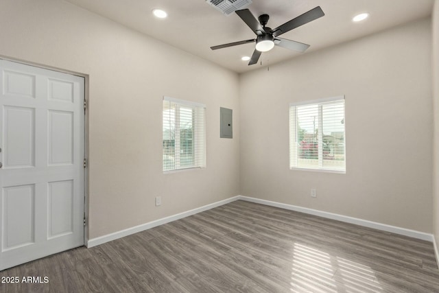 empty room with wood-type flooring, electric panel, a wealth of natural light, and ceiling fan