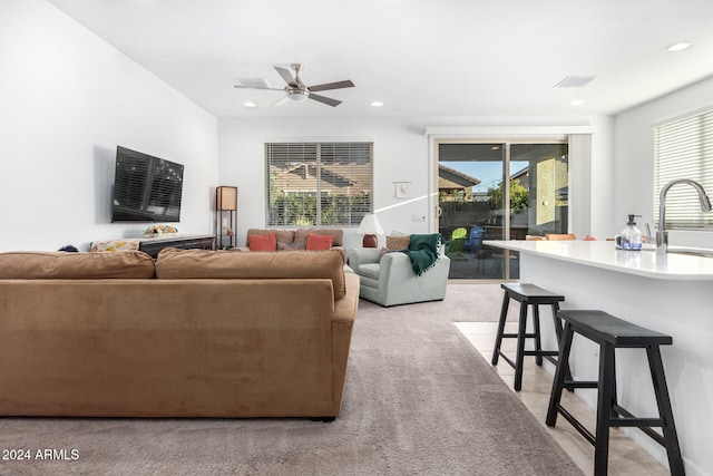 living room featuring a wealth of natural light, ceiling fan, and light colored carpet