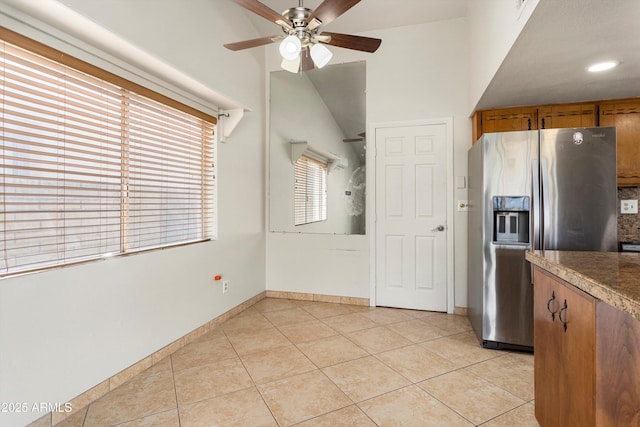 kitchen featuring baseboards, ceiling fan, stainless steel fridge with ice dispenser, brown cabinets, and light tile patterned flooring