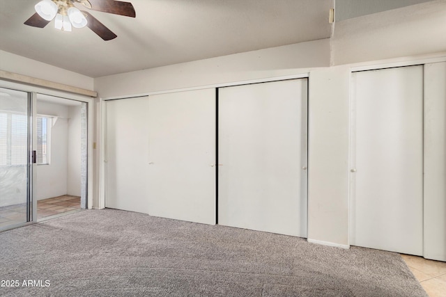 unfurnished bedroom with multiple closets, light carpet, and ceiling fan