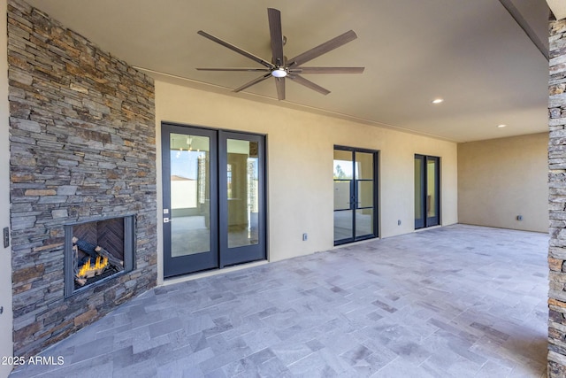 view of patio with ceiling fan and an outdoor stone fireplace