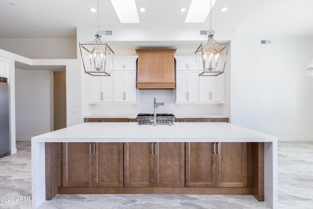 kitchen featuring a large island, wall chimney range hood, and an inviting chandelier