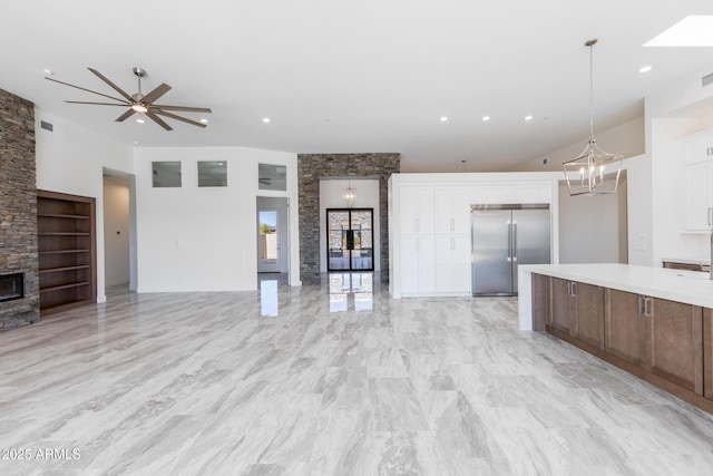 kitchen featuring built in features, a fireplace, white cabinets, decorative light fixtures, and built in fridge