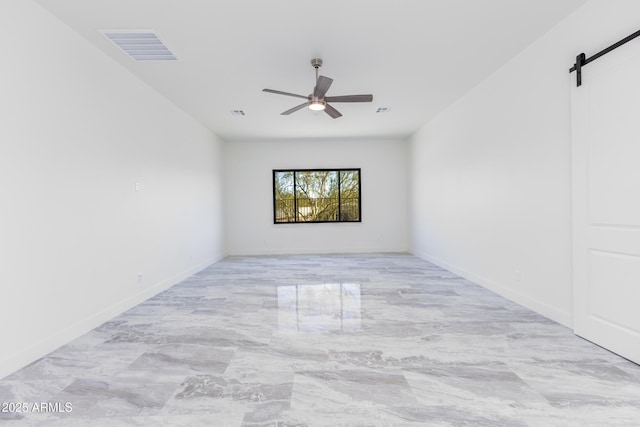 spare room featuring a barn door and ceiling fan