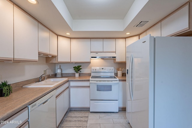 kitchen with white cabinetry, sink, a raised ceiling, white appliances, and light tile patterned floors