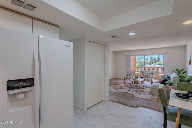 kitchen featuring light carpet and white fridge with ice dispenser