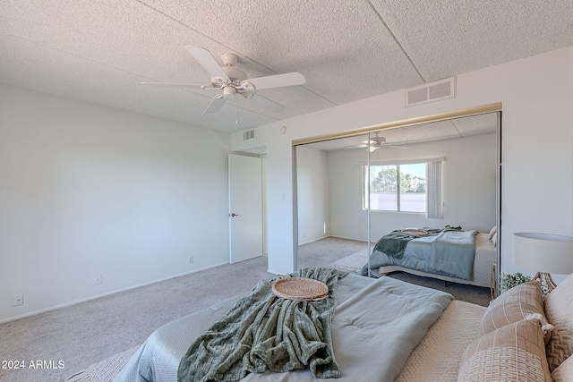 carpeted bedroom featuring ceiling fan, a closet, and a textured ceiling