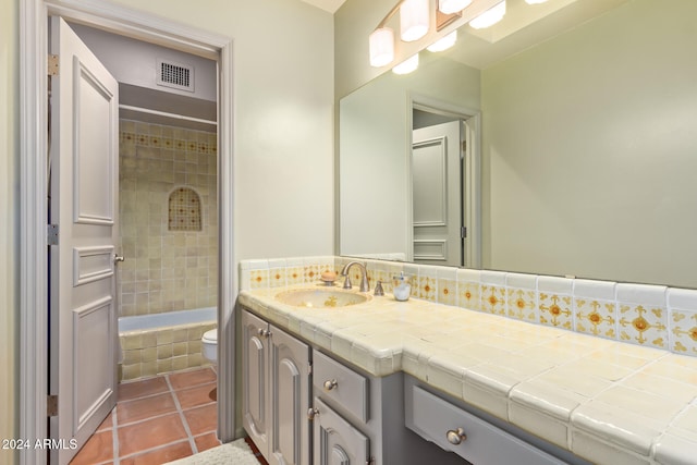 full bathroom with backsplash, tile patterned floors, vanity, tiled shower / bath combo, and toilet