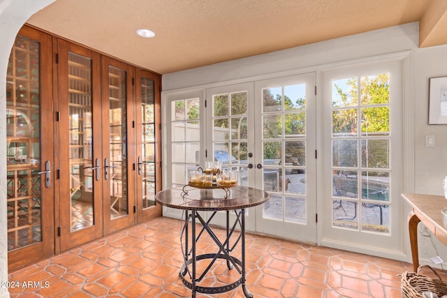 doorway to outside with light tile patterned floors, a textured ceiling, and french doors