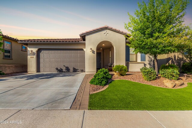 mediterranean / spanish house featuring a garage and a lawn