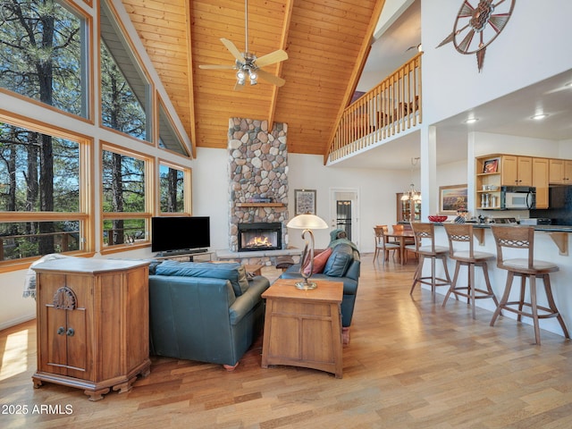 525 E Turkey Trl, Munds Park, AZ 86017 - living area with high vaulted ceiling, light wood-style floors, a ceiling fan, a stone fireplace, and a wooden ceiling with exposed beams