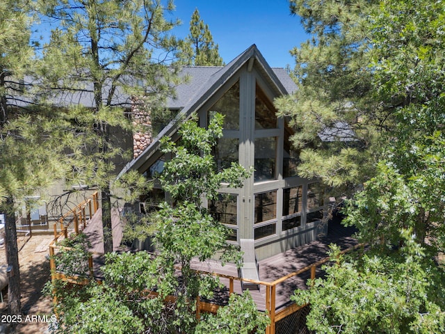 525 E Turkey Trl, Munds Park, AZ 86017 - rear view of property with stone siding, a sunroom, and roof with shingles