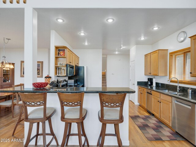 525 E Turkey Trl, Munds Park, AZ 86017 - kitchen with black appliances, open shelves, a breakfast bar, light wood finished floors, and a peninsula