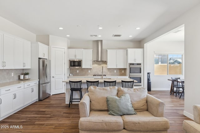 20606 E Avenida Del Valle Ct, Queen Creek, AZ 85142 - kitchen with visible vents, open floor plan, wall chimney range hood, white cabinets, and stainless steel appliances