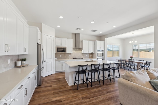 20606 E Avenida Del Valle Ct, Queen Creek, AZ 85142 - kitchen featuring wall chimney range hood, a sink, a chandelier, a breakfast bar, and stainless steel appliances