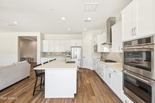 20606 E Avenida Del Valle Ct, Queen Creek, AZ 85142 - kitchen featuring wall chimney range hood, a kitchen breakfast bar, visible vents, a sink, and stainless steel appliances