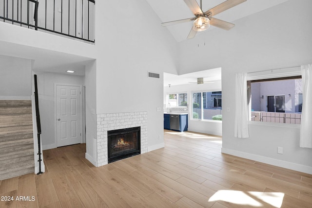 unfurnished living room with a fireplace, light hardwood / wood-style floors, high vaulted ceiling, and ceiling fan