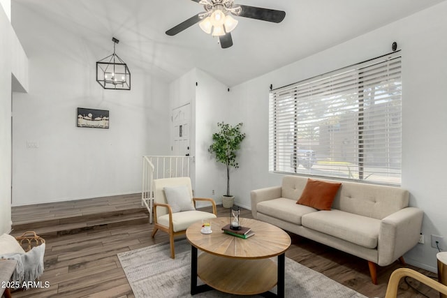 living room with ceiling fan with notable chandelier and hardwood / wood-style floors