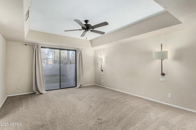 carpeted empty room featuring ceiling fan and a raised ceiling