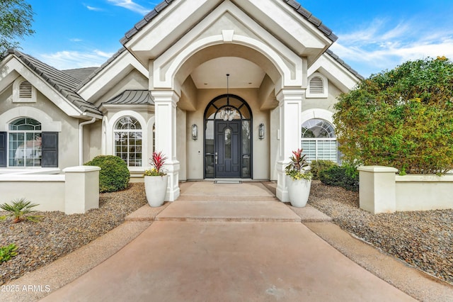 property entrance with stucco siding and a tile roof