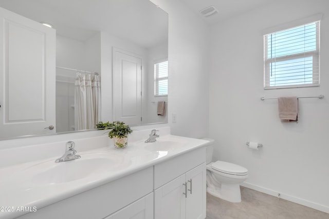 bathroom with double vanity, a sink, toilet, and baseboards