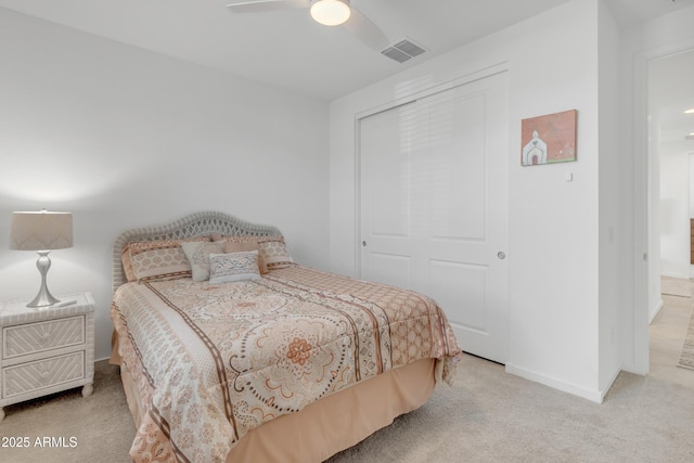 bedroom with a closet, visible vents, light carpet, ceiling fan, and baseboards