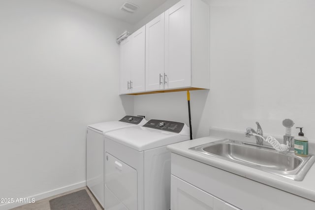 clothes washing area featuring washing machine and clothes dryer, cabinet space, visible vents, a sink, and baseboards