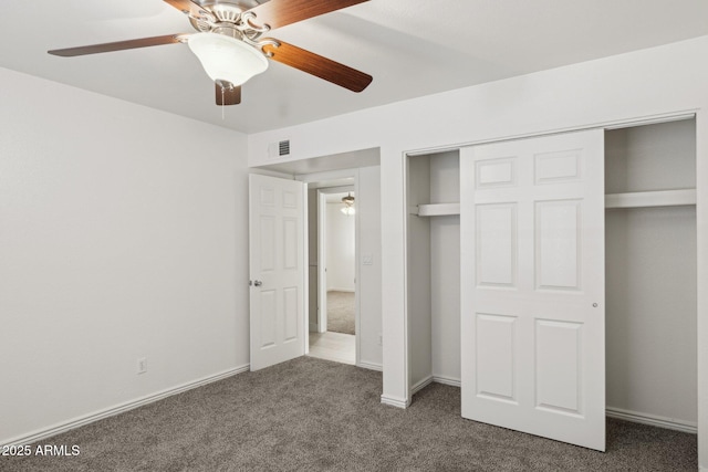 unfurnished bedroom with ceiling fan, dark carpet, and a closet