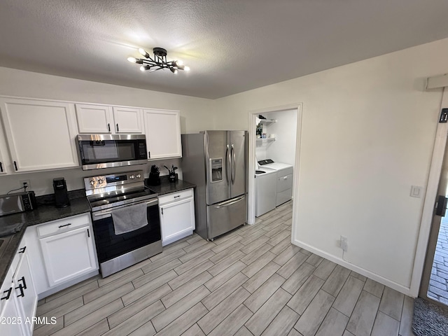 kitchen featuring white cabinets, dark countertops, stainless steel appliances, and washing machine and clothes dryer