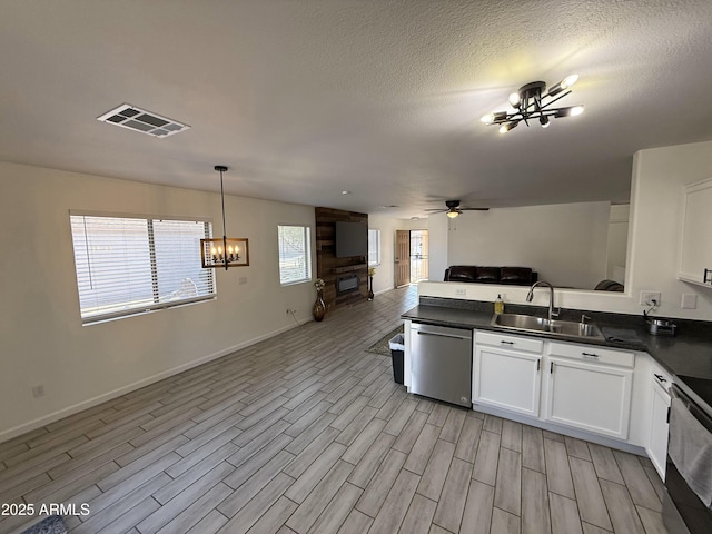 kitchen featuring dark countertops, visible vents, stainless steel dishwasher, open floor plan, and a sink