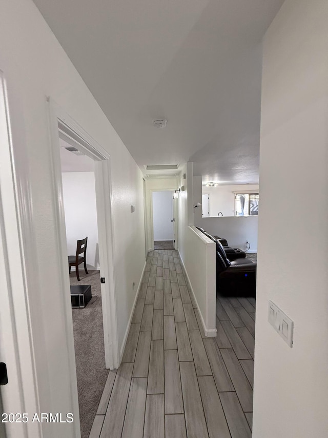 corridor featuring baseboards and wood finish floors