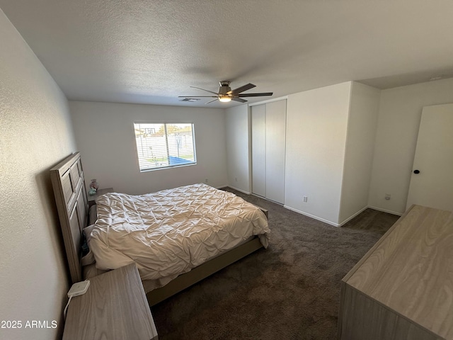 bedroom with baseboards, ceiling fan, a textured ceiling, carpet flooring, and a closet