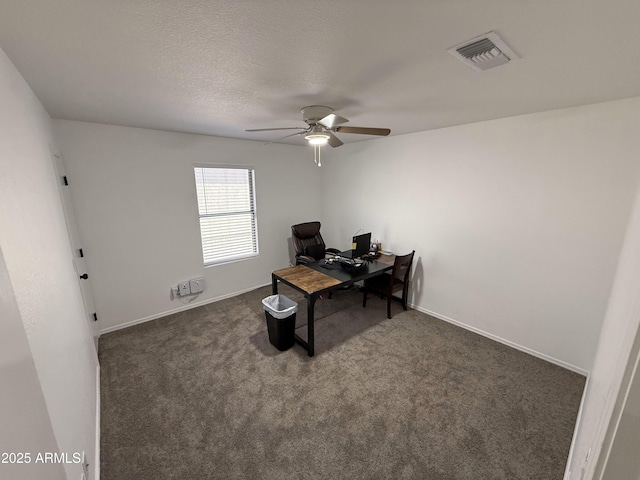 carpeted office featuring baseboards, a textured ceiling, visible vents, and a ceiling fan