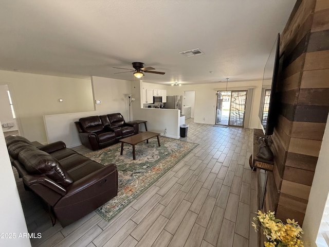 living room featuring wood finish floors, visible vents, and a ceiling fan